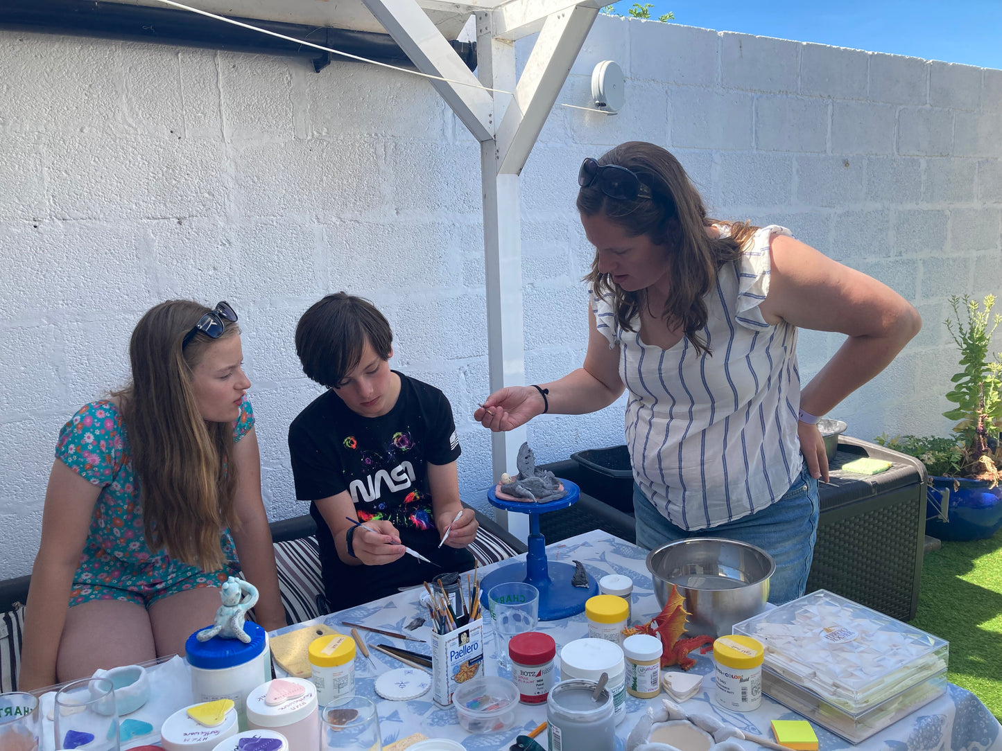 Two children in their early teens and their mum are enjoying creating sculptures of their choices in a private ceramic workshop on Portland at the Happy You And Mee Studio.