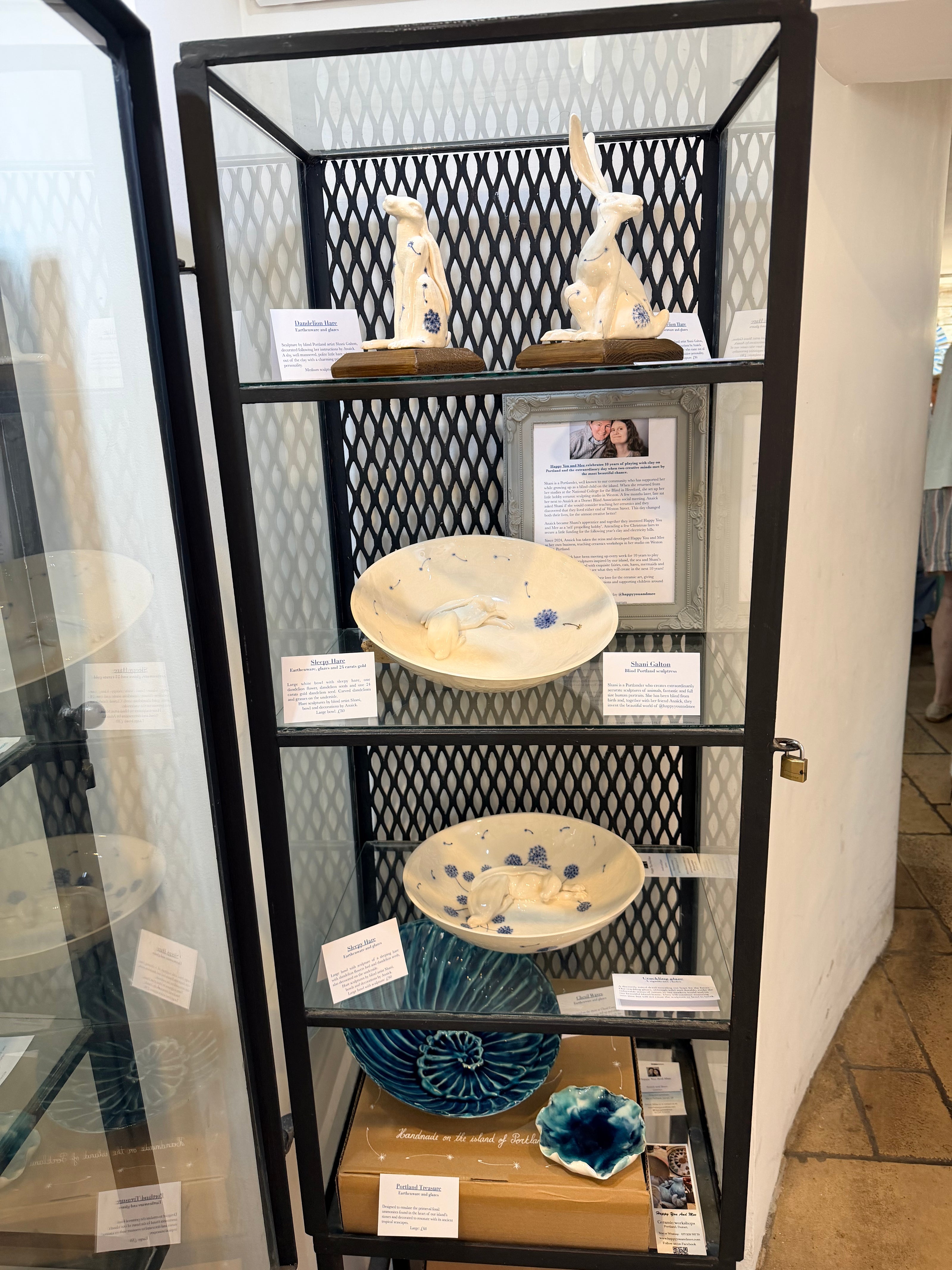 Inside the White Stones café and gallery, our dandelion hares sculptures and a large blue ammonite bowl are displayed in a black metal and glass display cabinet.
