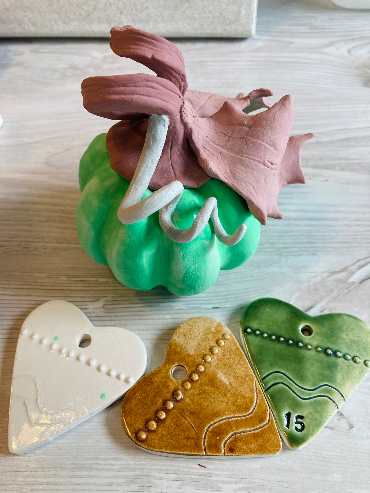 Ceramic pumpkin has been carefully covered in 3 different colour glazes, it stands near 3 small ceramic hearts which show the colours after they have been fired in the kiln